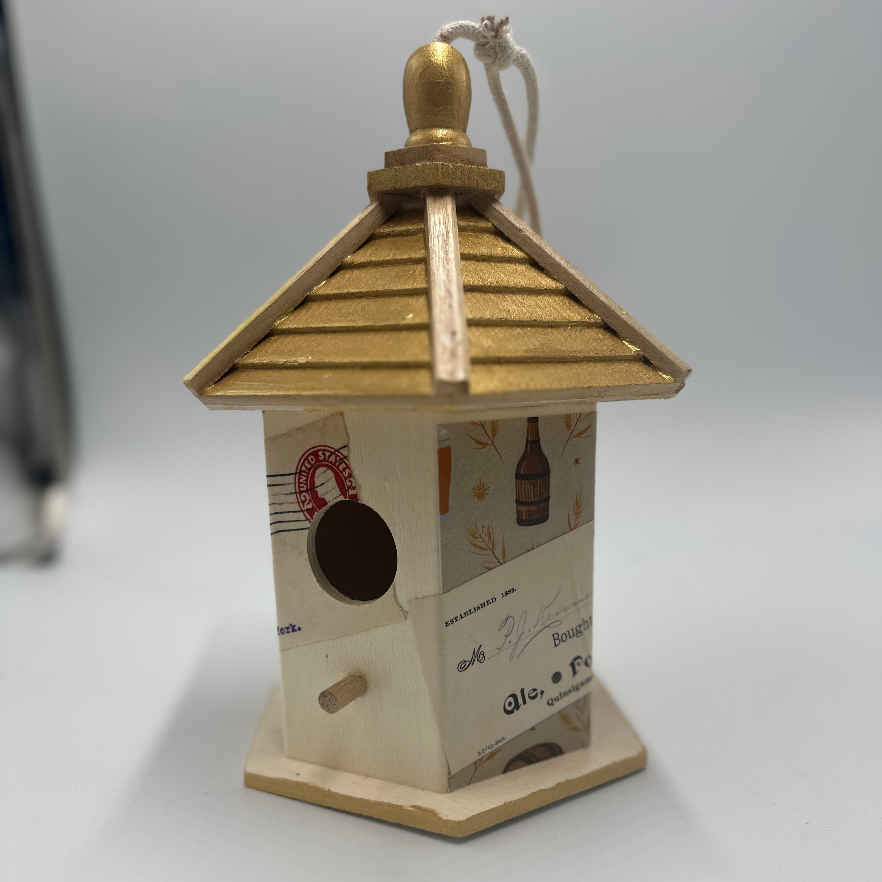 Decorative birdhouse with a gold roof on a white background