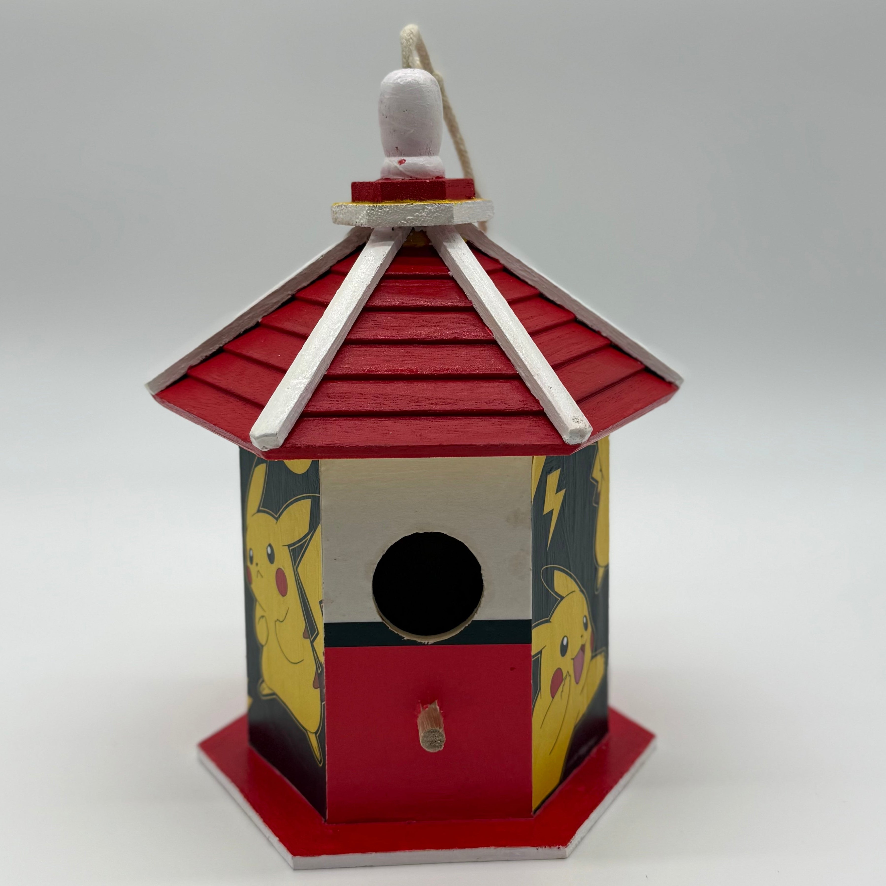 Decorative birdhouse with red roof and black and yellow design on a white background